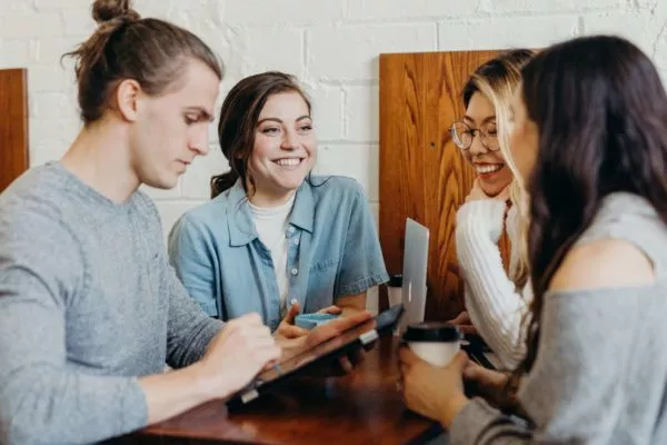Group of people having a conversation at a table with devices.